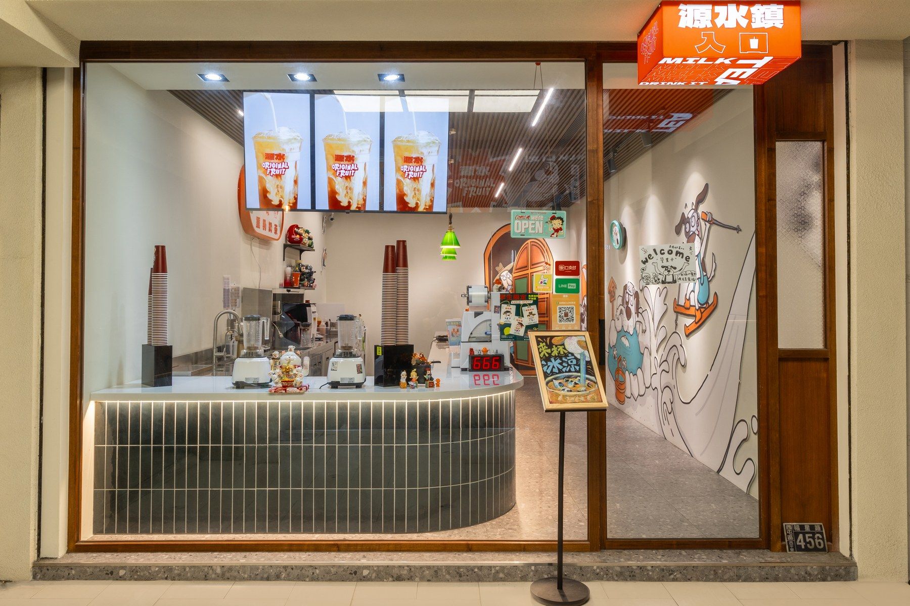 源水逢甲店夜間店面,整面玻璃內是弧形吧台與綠色長條磚檯面,右側牆是品牌手繪插畫,上方掛橘色發光招牌